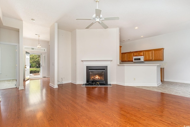 unfurnished living room with light wood-type flooring, ceiling fan, and a textured ceiling