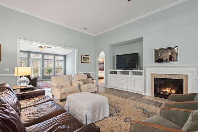 living room with hardwood / wood-style floors, ornamental molding, a premium fireplace, and ceiling fan