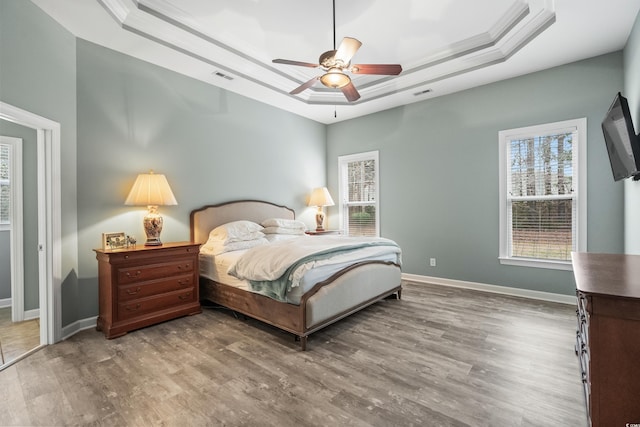 bedroom featuring a tray ceiling, ornamental molding, and hardwood / wood-style flooring