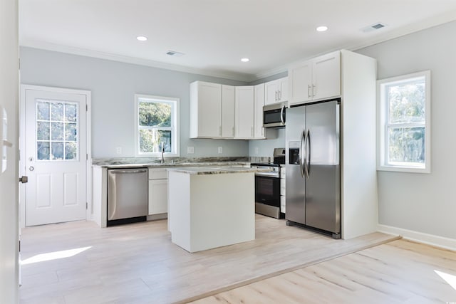 kitchen featuring light stone countertops, a kitchen island, light hardwood / wood-style floors, stainless steel appliances, and white cabinets