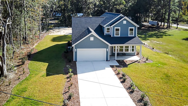 view of front of home featuring covered porch, a garage, and a front lawn