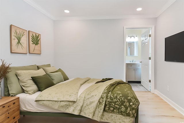 bedroom with crown molding, ensuite bath, sink, and light wood-type flooring