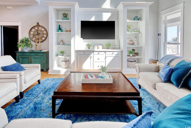 living room featuring wood-type flooring and built in shelves