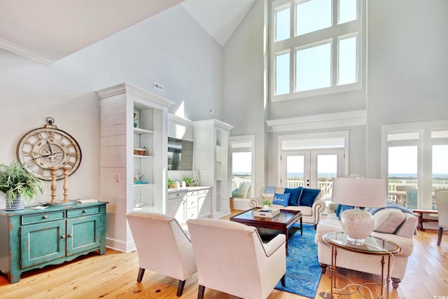 living room with light hardwood / wood-style floors, french doors, and a high ceiling