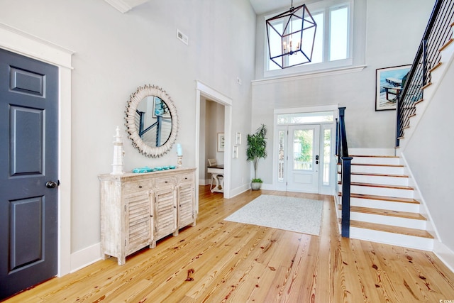 foyer entrance featuring wood-type flooring, a high ceiling, and a chandelier