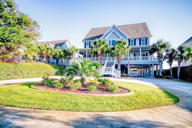 raised beach house featuring a front lawn, covered porch, and a carport