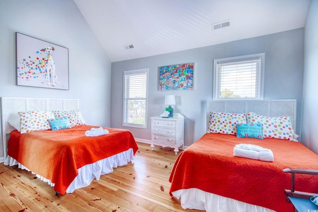 bedroom featuring multiple windows, wood-type flooring, and lofted ceiling