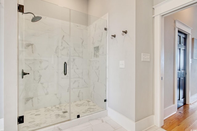 bathroom with wood-type flooring and an enclosed shower