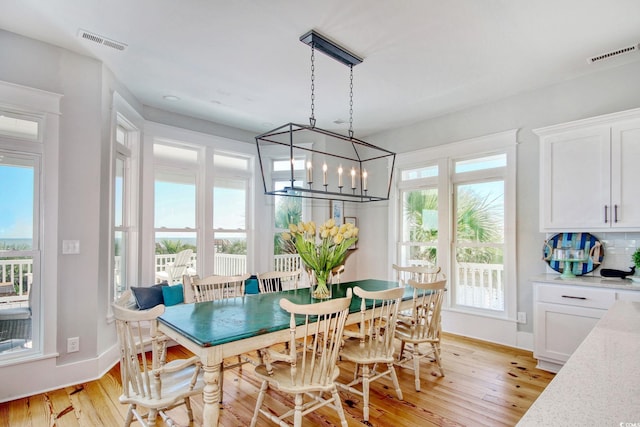 dining space featuring light hardwood / wood-style flooring, a notable chandelier, and a wealth of natural light