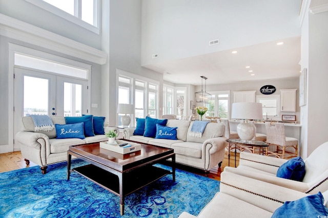 living room featuring french doors, a towering ceiling, plenty of natural light, and dark hardwood / wood-style floors