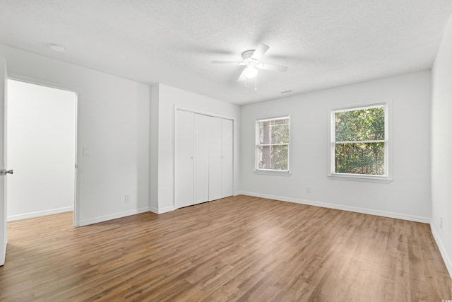 unfurnished bedroom with light hardwood / wood-style flooring, a textured ceiling, a closet, and ceiling fan