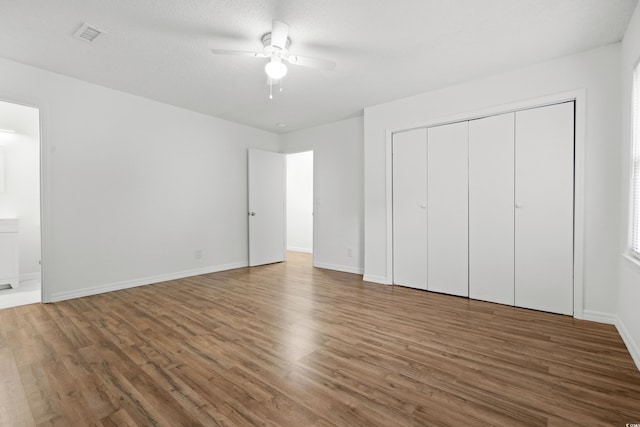 unfurnished bedroom featuring dark wood-type flooring, a textured ceiling, a closet, and ceiling fan