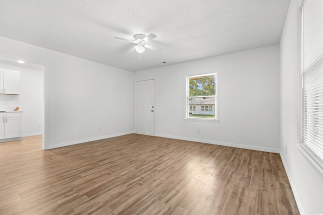 unfurnished room featuring light hardwood / wood-style floors, a textured ceiling, and ceiling fan