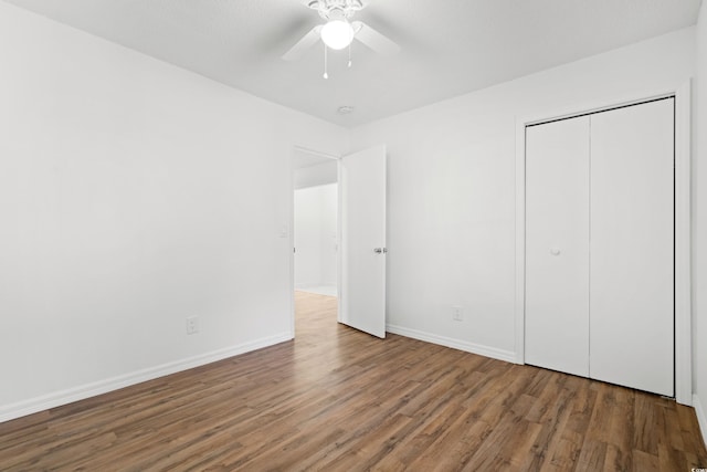 unfurnished bedroom with dark hardwood / wood-style flooring, a closet, and ceiling fan