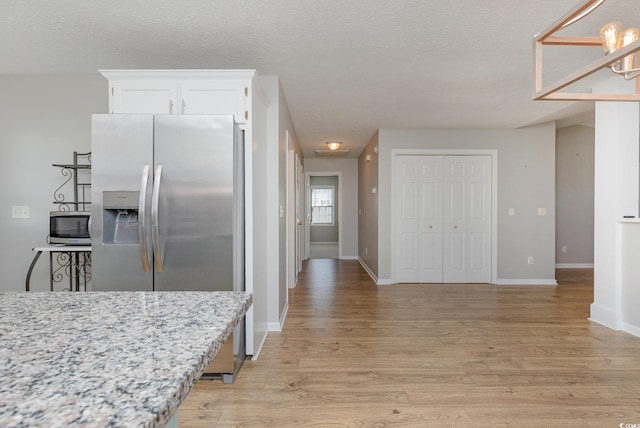 kitchen featuring light stone counters, white cabinetry, light hardwood / wood-style floors, and appliances with stainless steel finishes