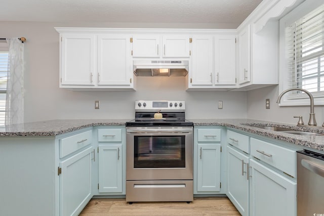 kitchen with stainless steel appliances, light stone countertops, sink, and light hardwood / wood-style floors