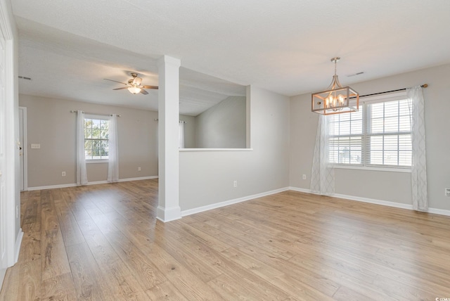 unfurnished room featuring ceiling fan with notable chandelier, a textured ceiling, and light wood-type flooring