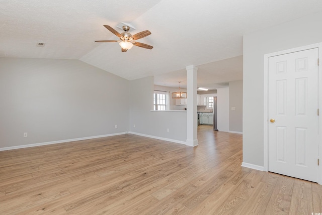 unfurnished living room with ceiling fan with notable chandelier, vaulted ceiling, a textured ceiling, and light wood-type flooring