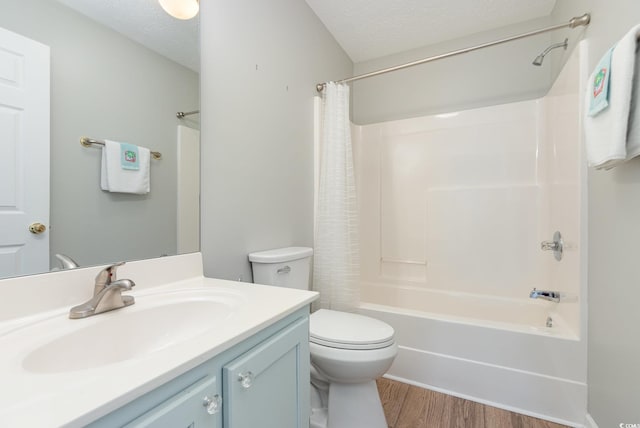 full bathroom with shower / bathtub combination with curtain, hardwood / wood-style flooring, vanity, a textured ceiling, and toilet