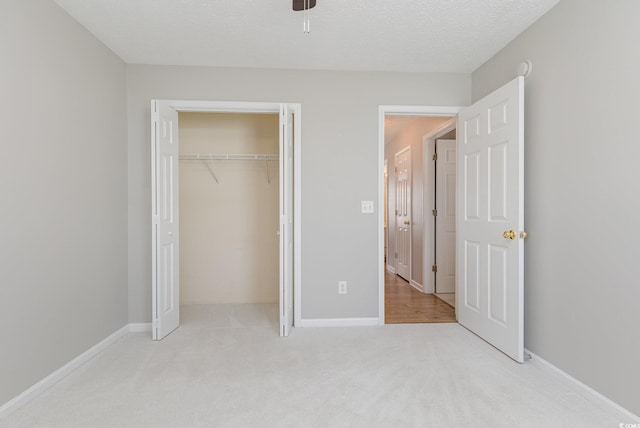 unfurnished bedroom featuring light carpet, a closet, and a textured ceiling