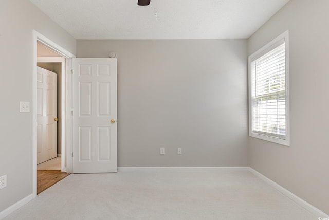 spare room featuring plenty of natural light, light colored carpet, and ceiling fan