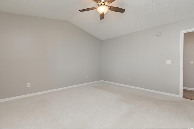 spare room featuring ceiling fan, carpet floors, vaulted ceiling, and a textured ceiling