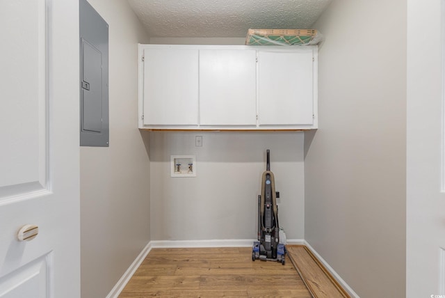 laundry area with light hardwood / wood-style flooring, electric panel, cabinets, washer hookup, and a textured ceiling