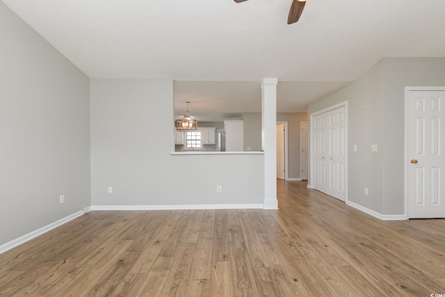 unfurnished living room with a textured ceiling, ceiling fan, and light wood-type flooring