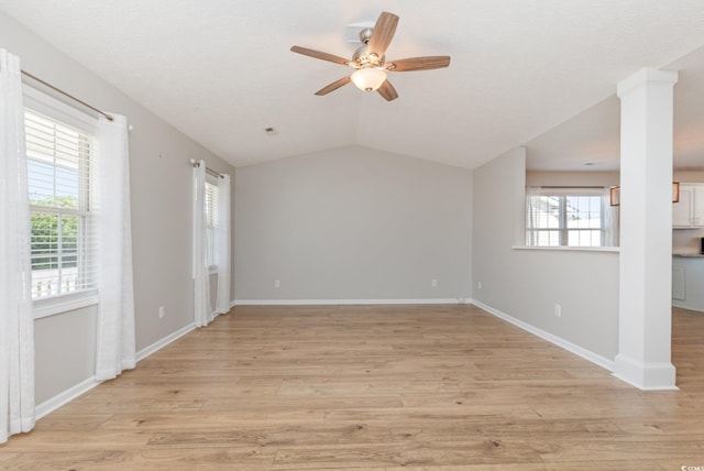 unfurnished room featuring ceiling fan, light wood-type flooring, a textured ceiling, vaulted ceiling, and ornate columns