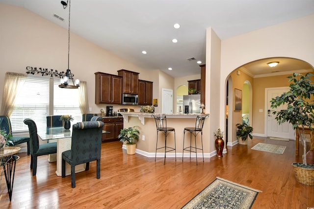 kitchen with appliances with stainless steel finishes, lofted ceiling, and light hardwood / wood-style floors