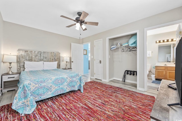 bedroom with a closet, hardwood / wood-style flooring, connected bathroom, and ceiling fan