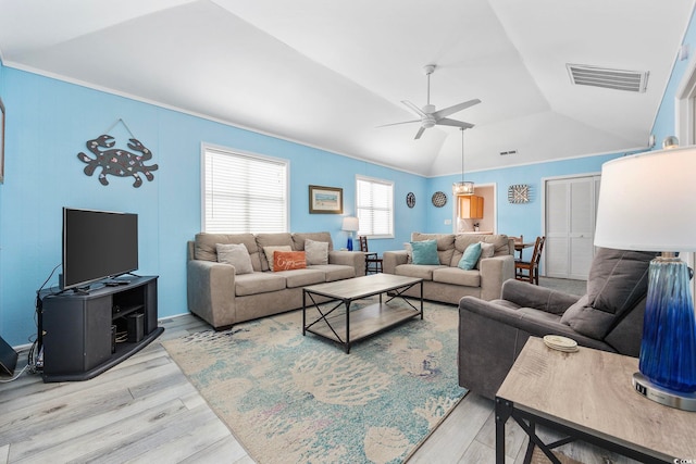 living area with visible vents, ornamental molding, ceiling fan, light wood-style floors, and lofted ceiling