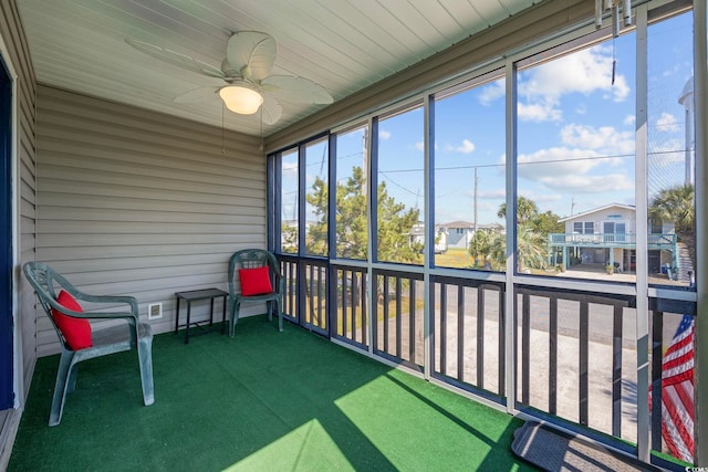 unfurnished sunroom featuring ceiling fan and a residential view