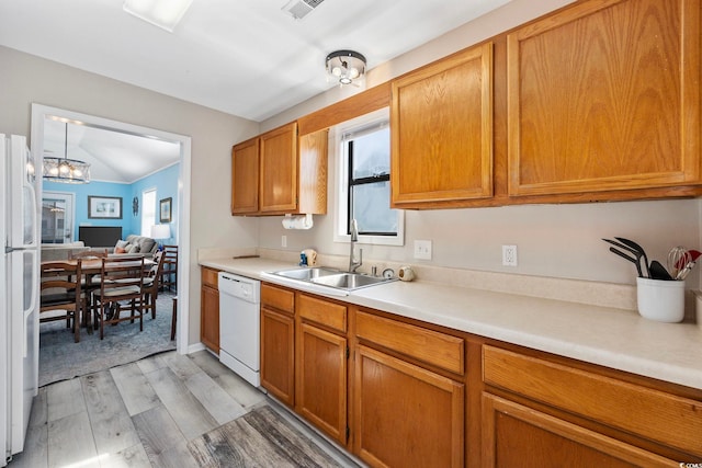 kitchen with white appliances, sink, light hardwood / wood-style floors, lofted ceiling, and an inviting chandelier