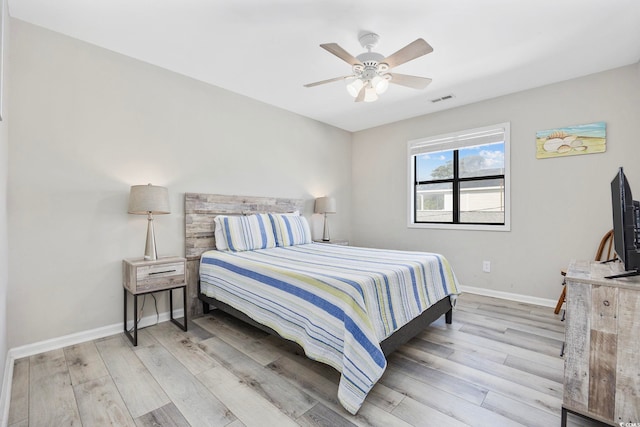 bedroom with visible vents, light wood-type flooring, baseboards, and a ceiling fan