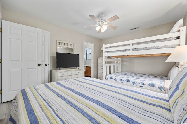 bedroom featuring light hardwood / wood-style flooring, ensuite bathroom, a closet, and ceiling fan