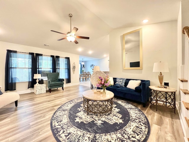 living room with light hardwood / wood-style floors, vaulted ceiling, and ceiling fan