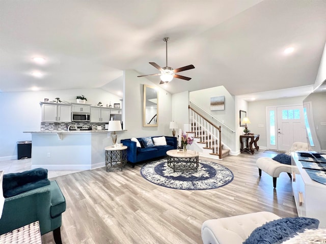 living room featuring light hardwood / wood-style floors, ceiling fan, and vaulted ceiling