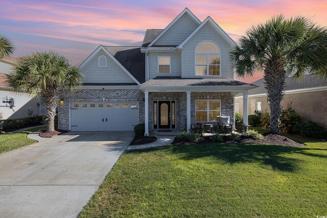 view of front of property featuring a garage, a lawn, and a porch