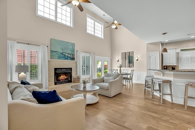 1002 Summers Pl, North Myrtle Beach, SC 29582 - living area featuring ceiling fan, a wainscoted wall, light wood finished floors, a tiled fireplace, and a high ceiling