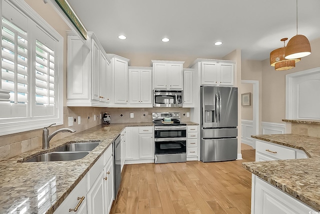1002 Summers Pl, North Myrtle Beach, SC 29582 - kitchen with white cabinets, light stone counters, a sink, light wood-type flooring, and appliances with stainless steel finishes