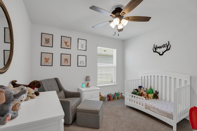 carpeted bedroom with ceiling fan and a crib