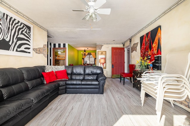 living room featuring ceiling fan, a textured ceiling, ornamental molding, and light hardwood / wood-style flooring