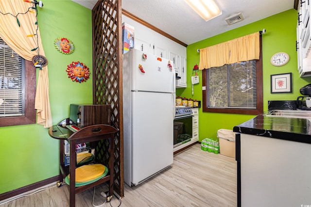 kitchen featuring light hardwood / wood-style flooring, crown molding, white refrigerator, black electric range, and white cabinetry