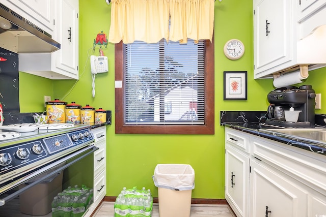 kitchen featuring white cabinetry, light wood-type flooring, extractor fan, and stove