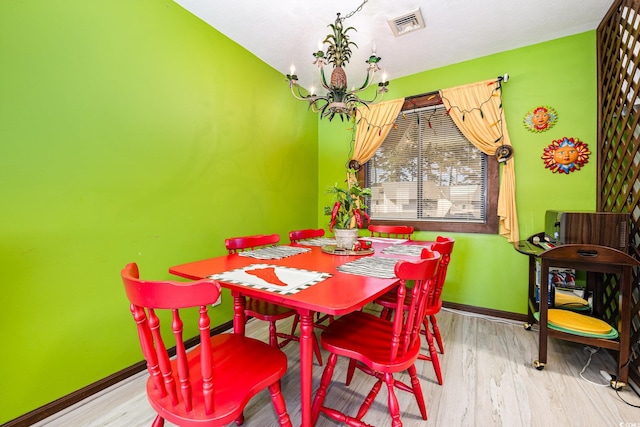 dining room with light hardwood / wood-style flooring and an inviting chandelier