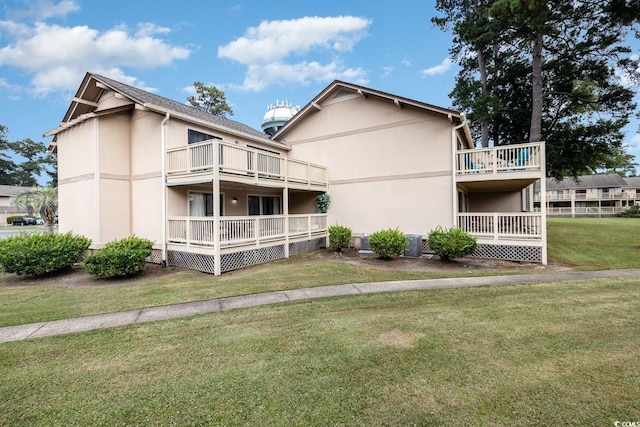 back of house featuring a balcony, central AC, and a lawn