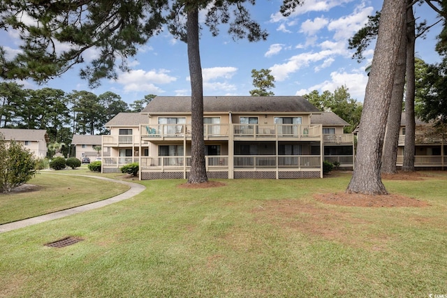 rear view of house with a lawn and a balcony