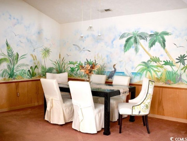 dining area featuring dark carpet, lofted ceiling, and wood walls