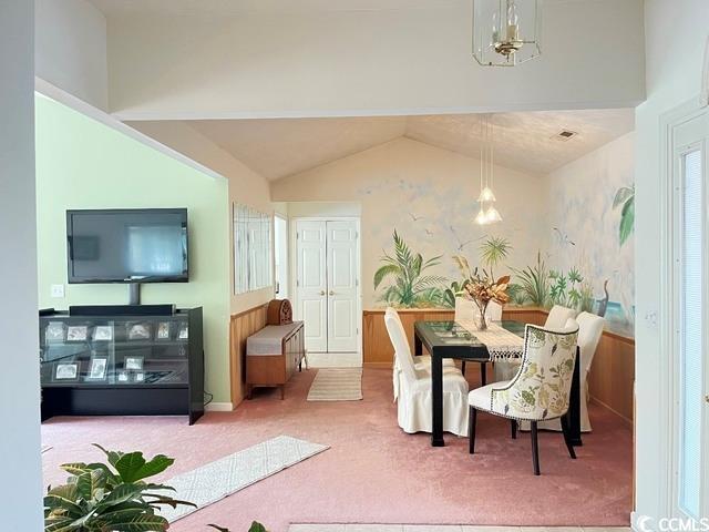 carpeted dining area featuring lofted ceiling and a chandelier